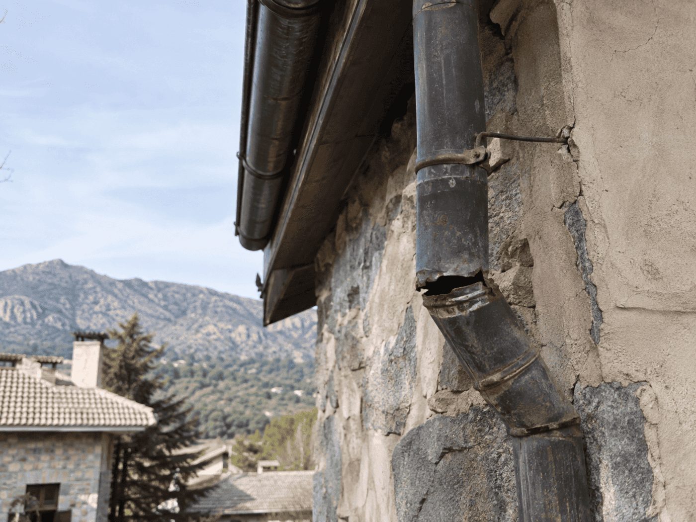 Bajante metálico oxidado y con rotura en un tramo, en una vivienda de la Sierra de Madrid — reparado por reparaciondetejados.madrid.
