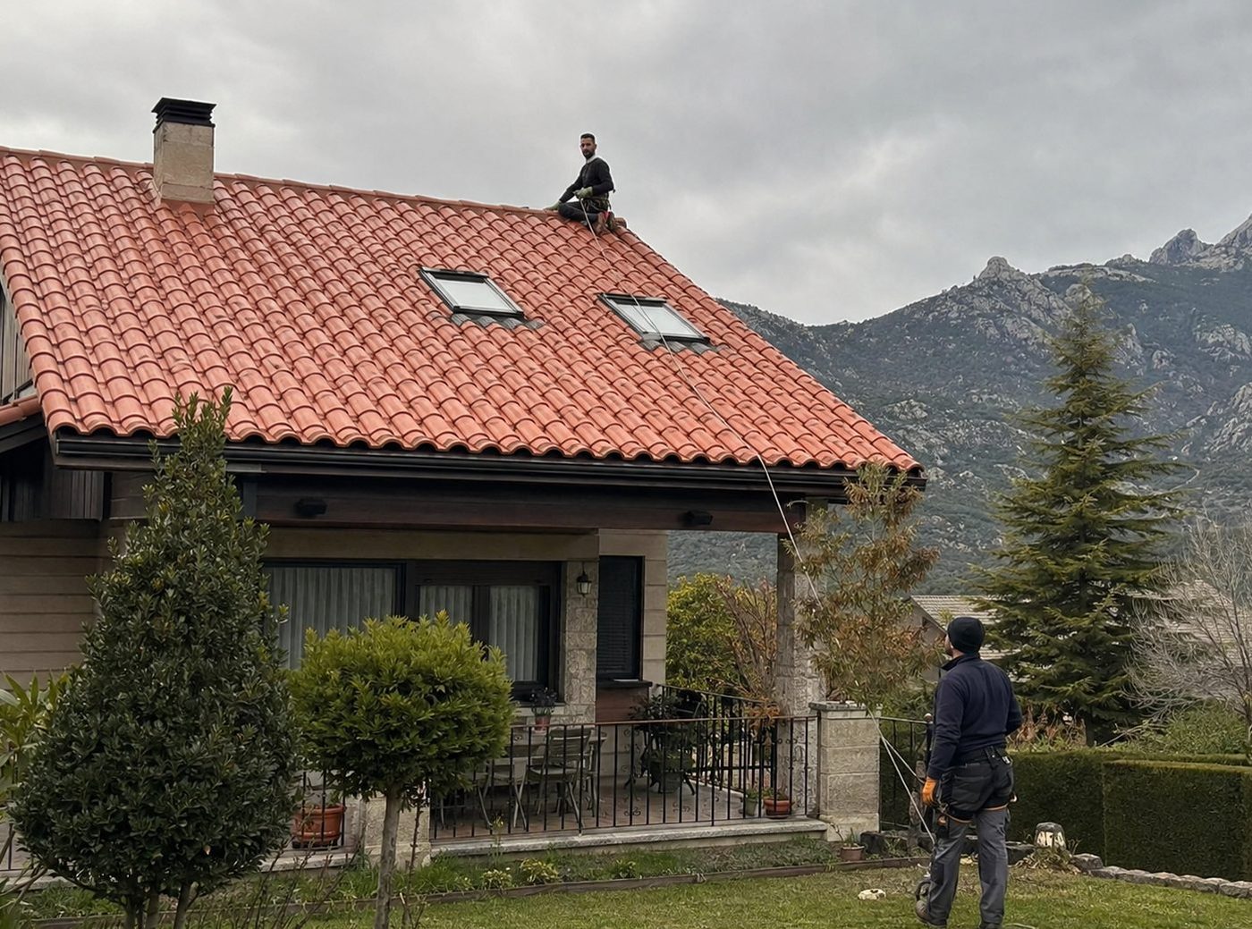 Dos técnicos de reparaciondetejados.madrid realizando una reparación de tejado en la Sierra de Madrid, con equipo de seguridad para trabajos en altura.